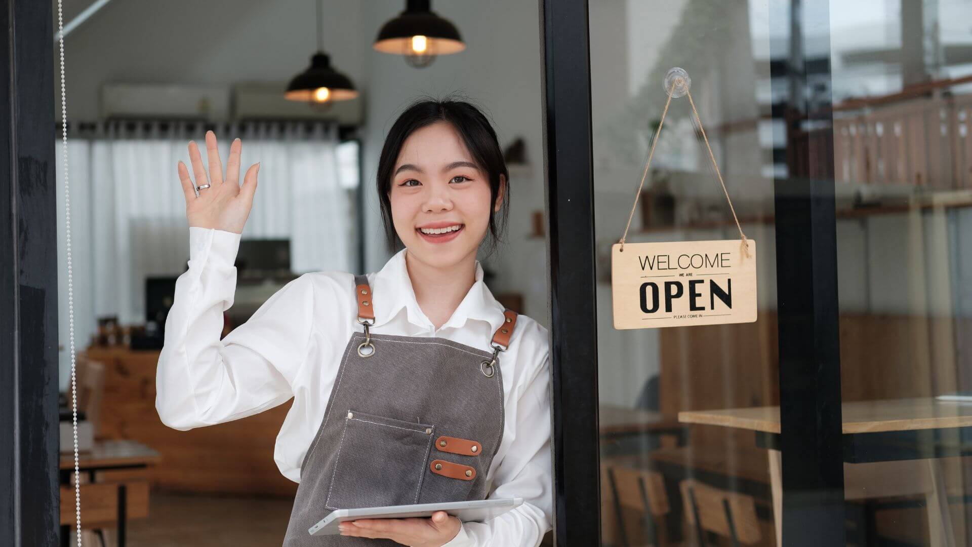 beautiful-smiling-barista-waitress-with-open-sign-in-front-cafe-welcoming-customer-hand-waving-royalty