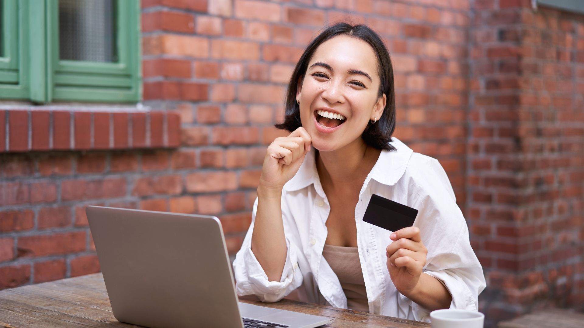 Smiling woman holding credit card and using laptop for online payment, representing BNPL digital finance in Malaysia.