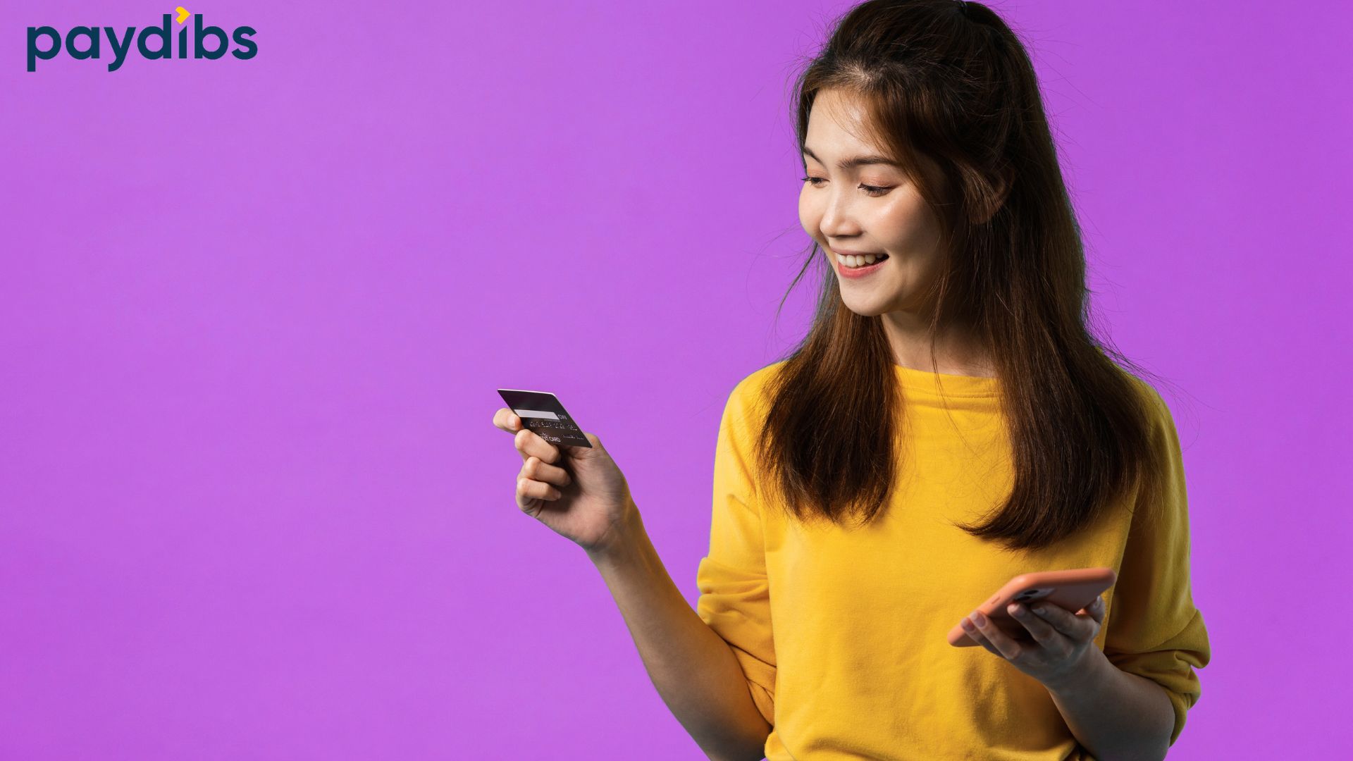 Smiling woman in a yellow shirt holding a credit card and a smartphone against a purple background, with the Paydibs logo in the top left.