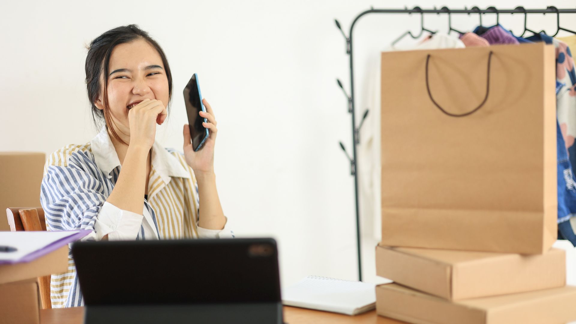 Young Asian phone calling in fashion store smiling happily