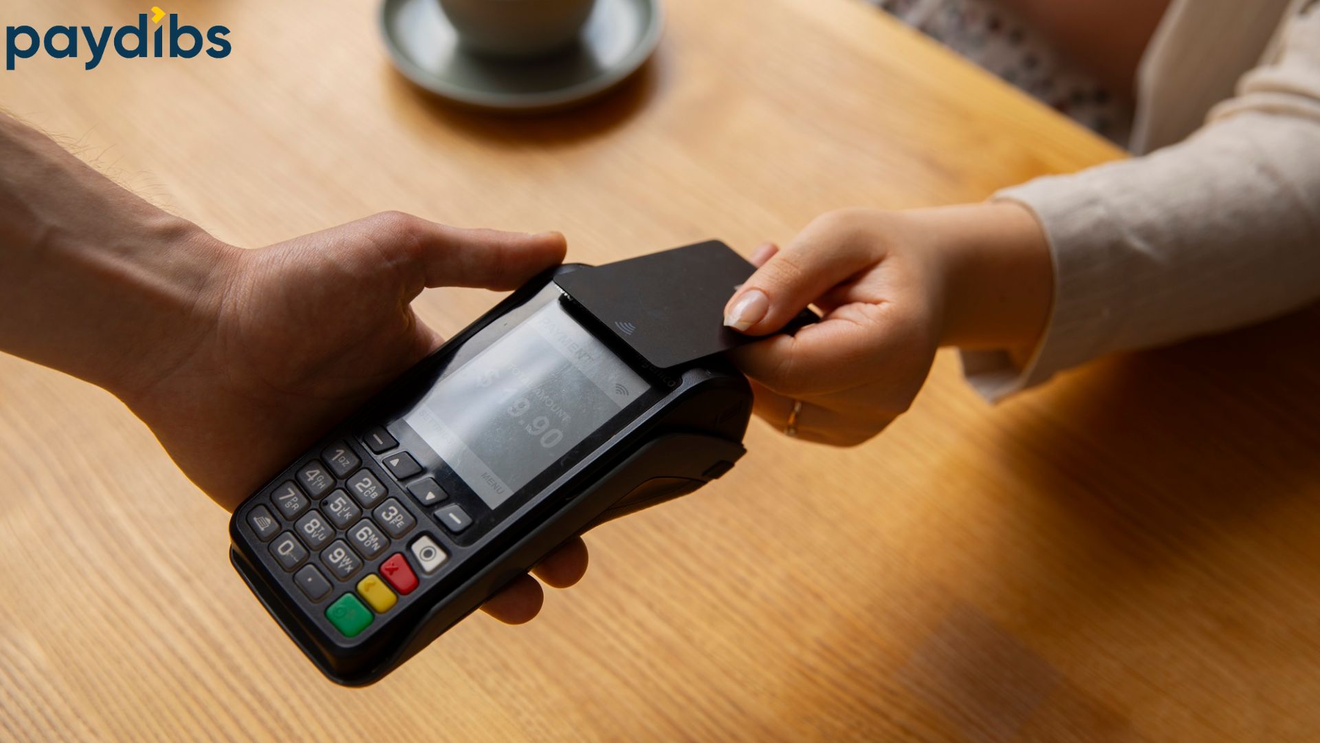 A woman using black payment card to tap and pay on a pos terminal