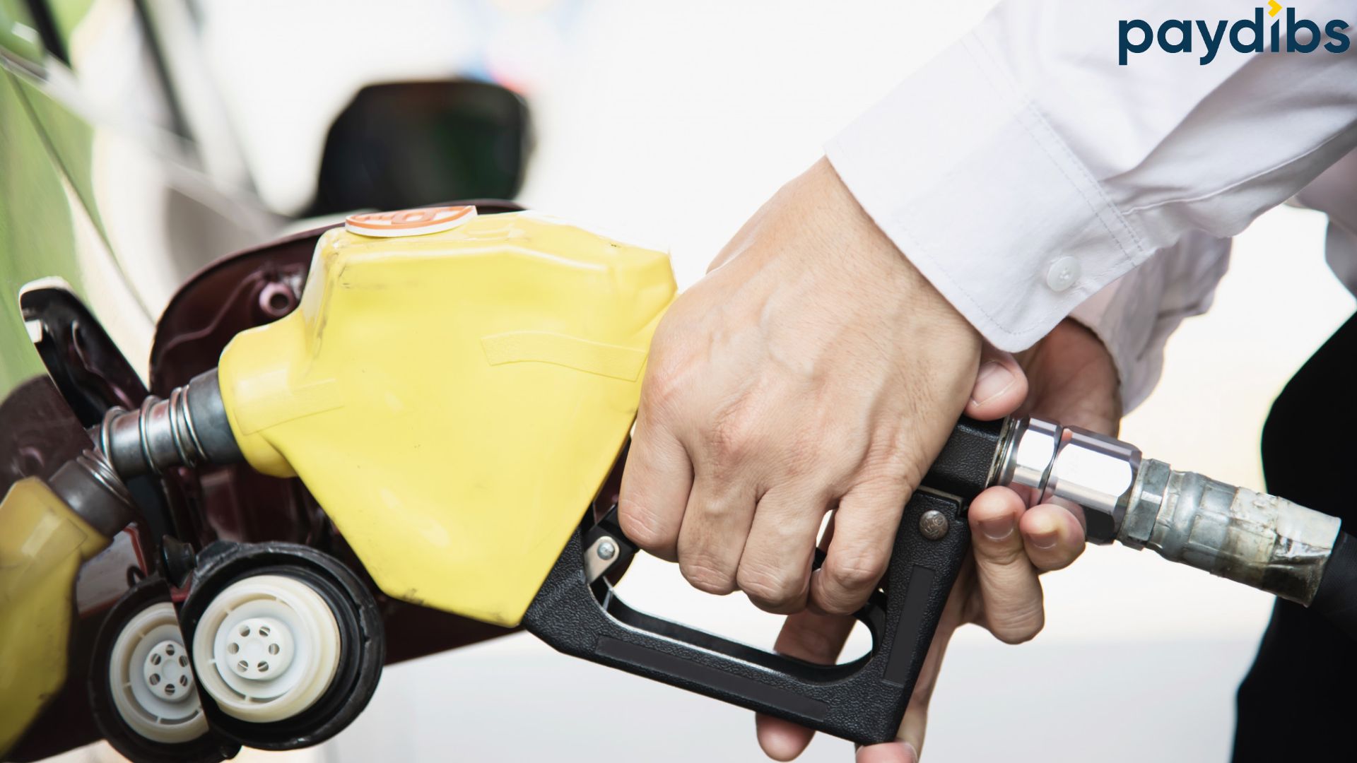 Man holding fuel pump filing up his vehicle after checking fuel price Malaysia.