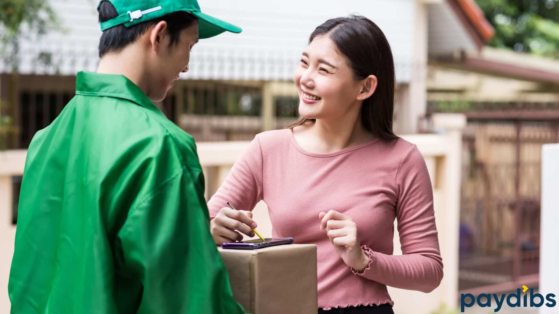 A woman smiling to delivery man while signing acknowledgement of receiving the parcel